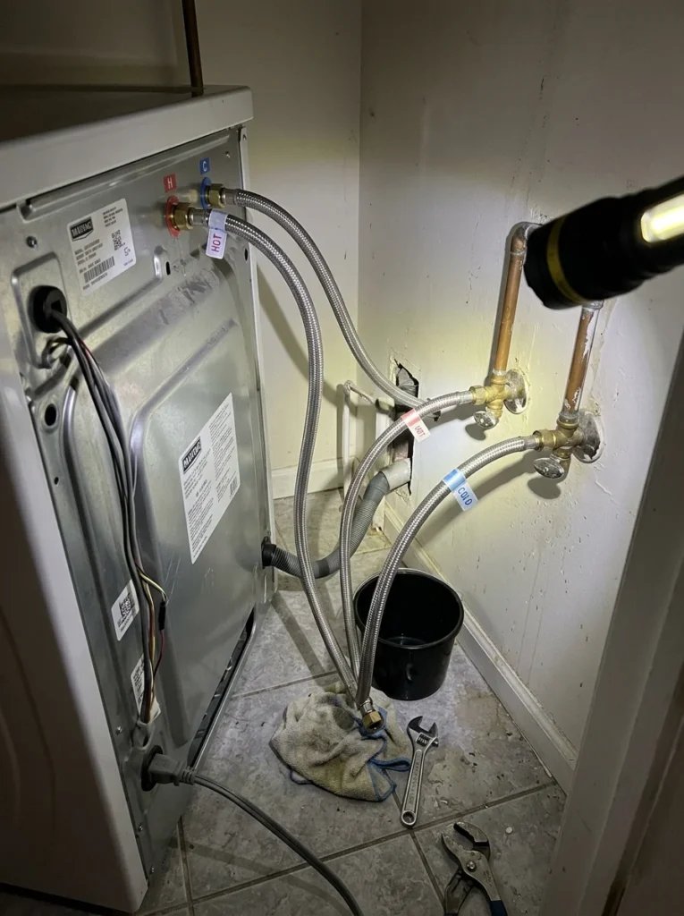 Checking behind a washing machine for hidden water leaks.