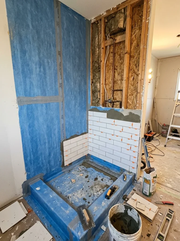 Waterproof membrane installed behind bathroom wall tiles.